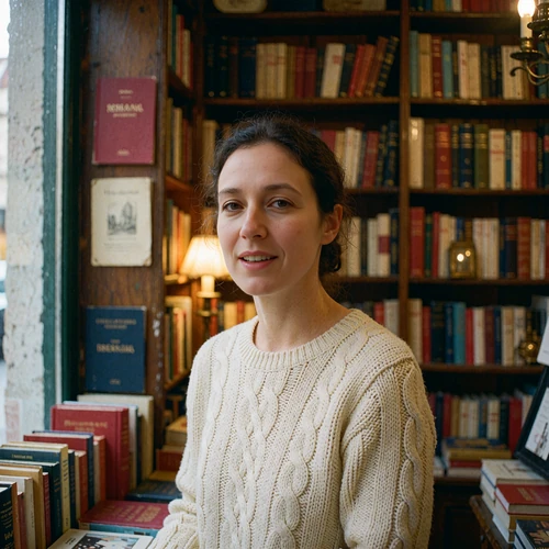 Woman near the window of a small European bookshop, turning to smile at the camera